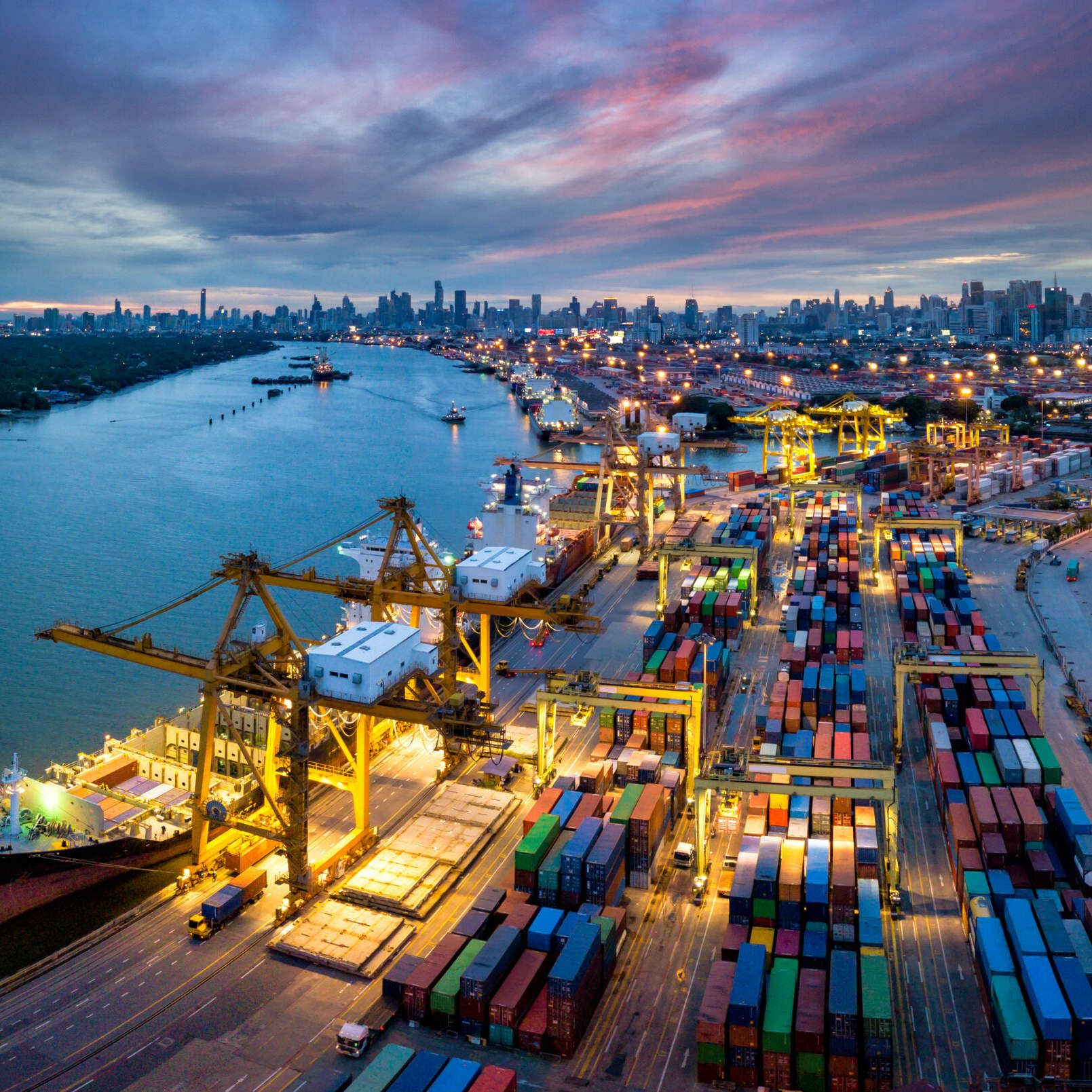 Aerial view of international port with Crane loading containers Aerial view of international port with Crane loading containers in import export business logistics with cityscape of Bangkok city Thailand at night